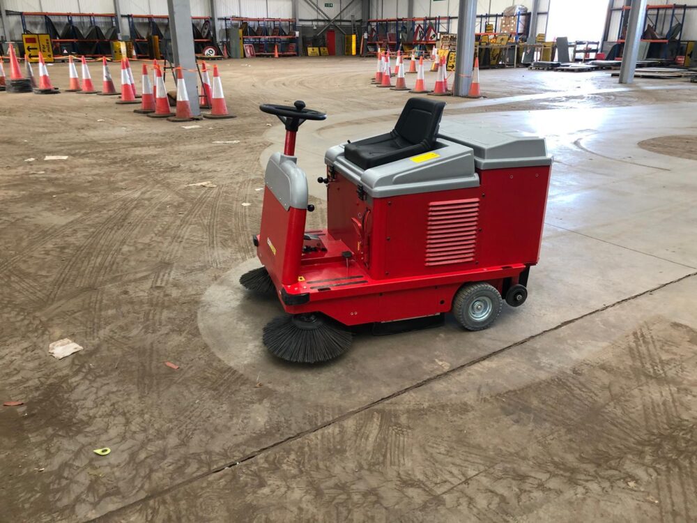 A red MAC sweeper in the middle of a warehouse floor.