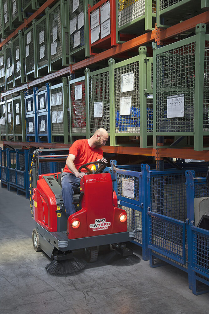 Person sitting on sweeper in a warehouse.