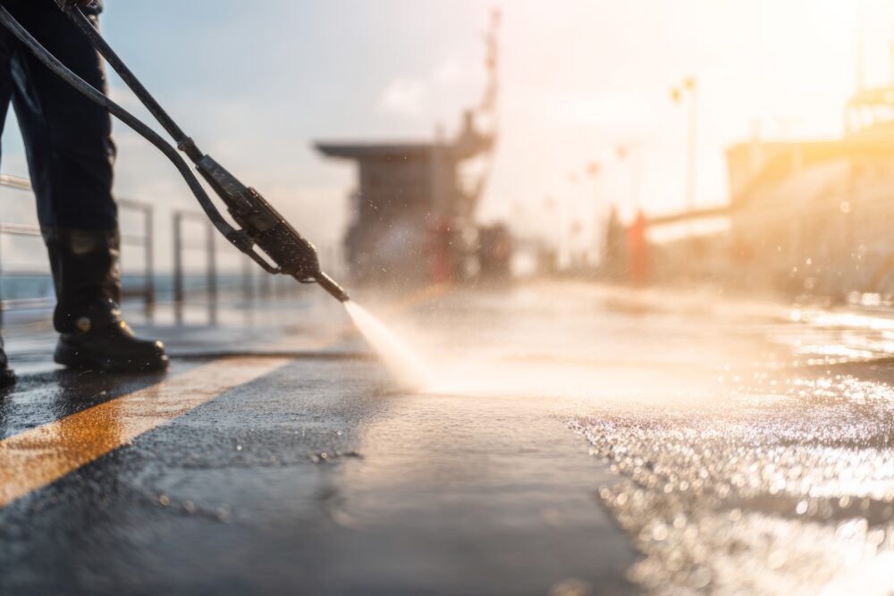 A pressure washer being used on the floor of ship deck.